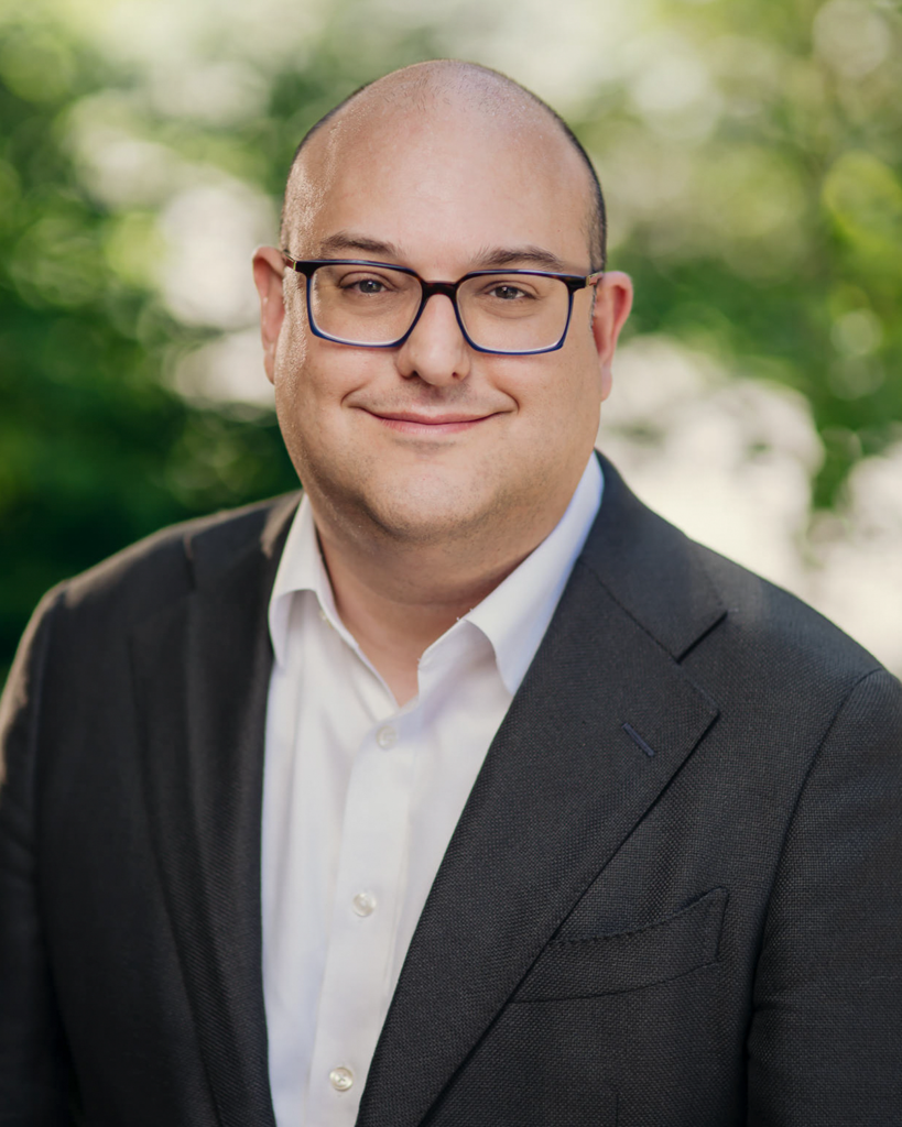 low joshua 2024 headshot, man with glasses, a white shirt and green blazer
